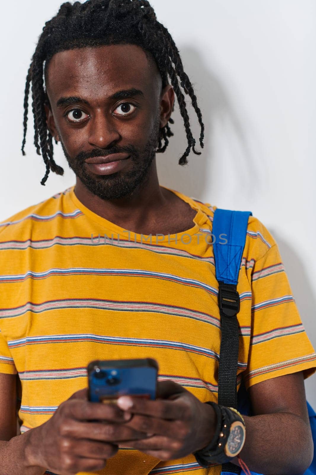 African American teenager engages with his smartphone against a pristine white background, encapsulating the essence of contemporary digital connectivity and youth culture.