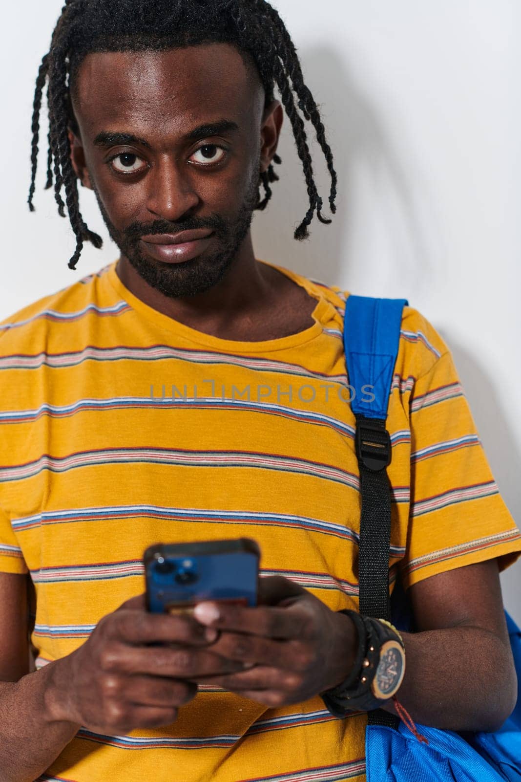 African American teenager engages with his smartphone against a pristine white background, encapsulating the essence of contemporary digital connectivity and youth culture.