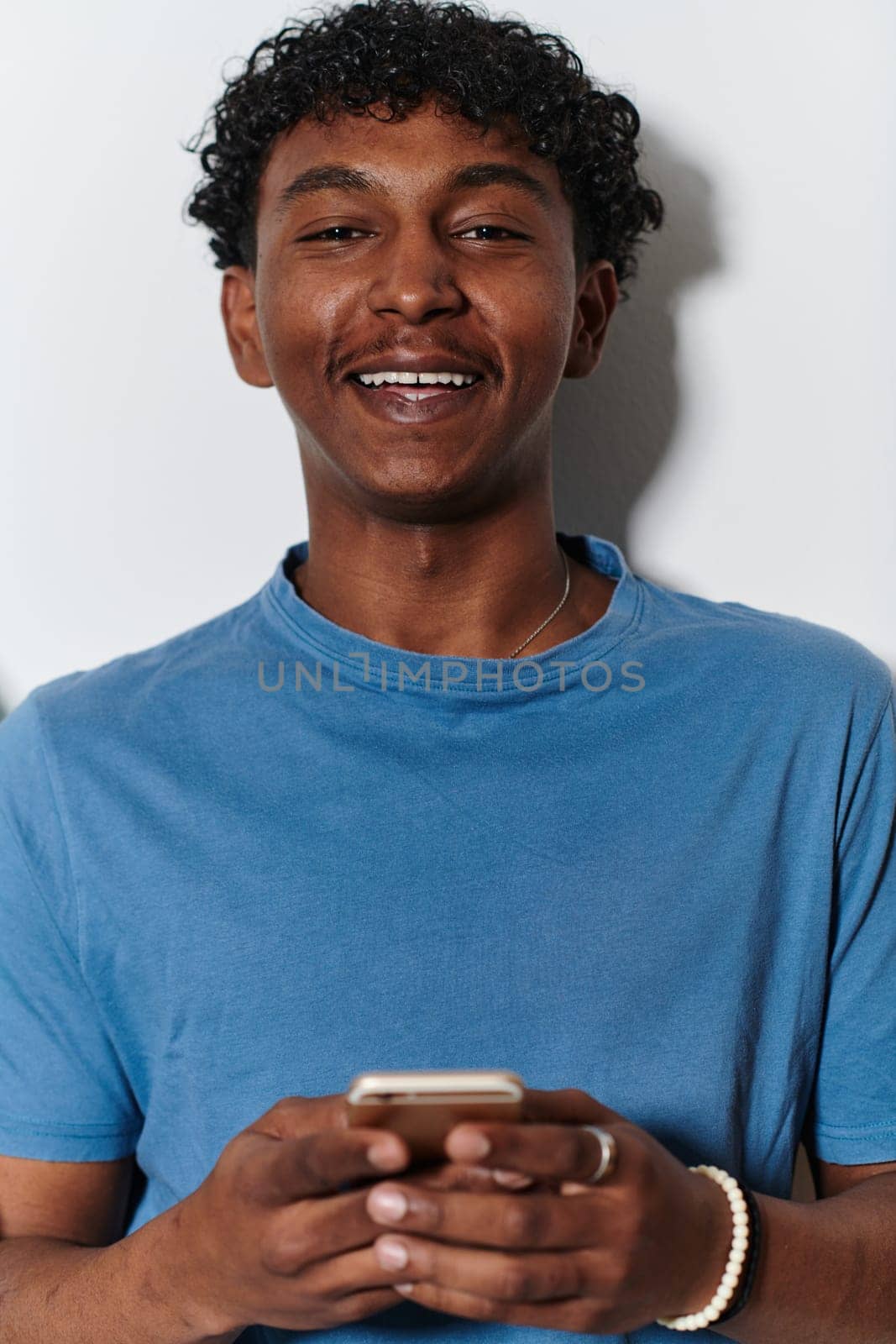 African American teenager engages with his smartphone against a pristine white background, encapsulating the essence of contemporary digital connectivity and youth culture.