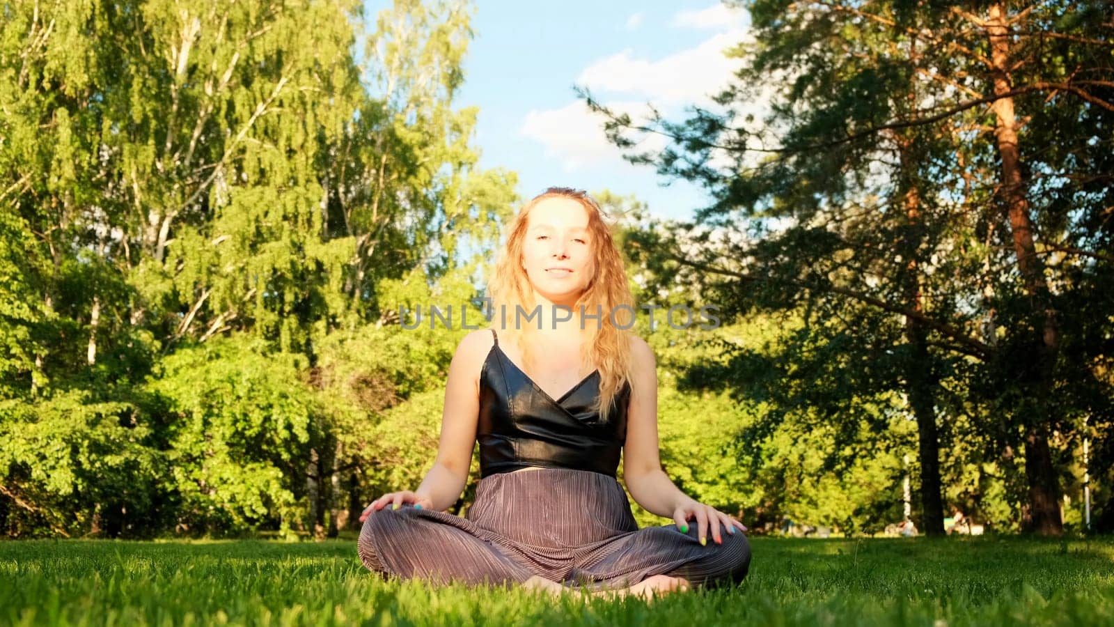 Meditation in the lotus position. Concept. A beautiful woman sitting in a clearing and meditating with her legs crossed. High quality 4k footage