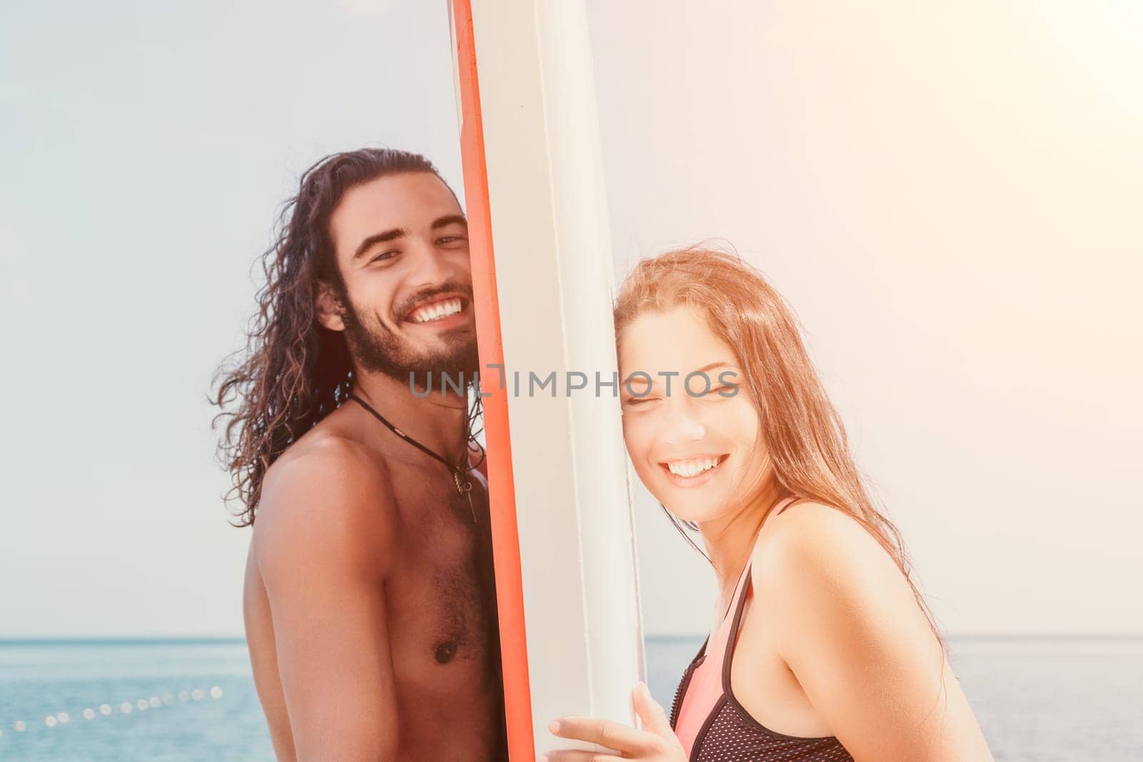 Woman man sea sup. Close up portrait of beautiful young caucasian woman with black hair and freckles looking at camera and smiling. Cute woman portrait in a pink bikini posing on sup board in the sea by panophotograph