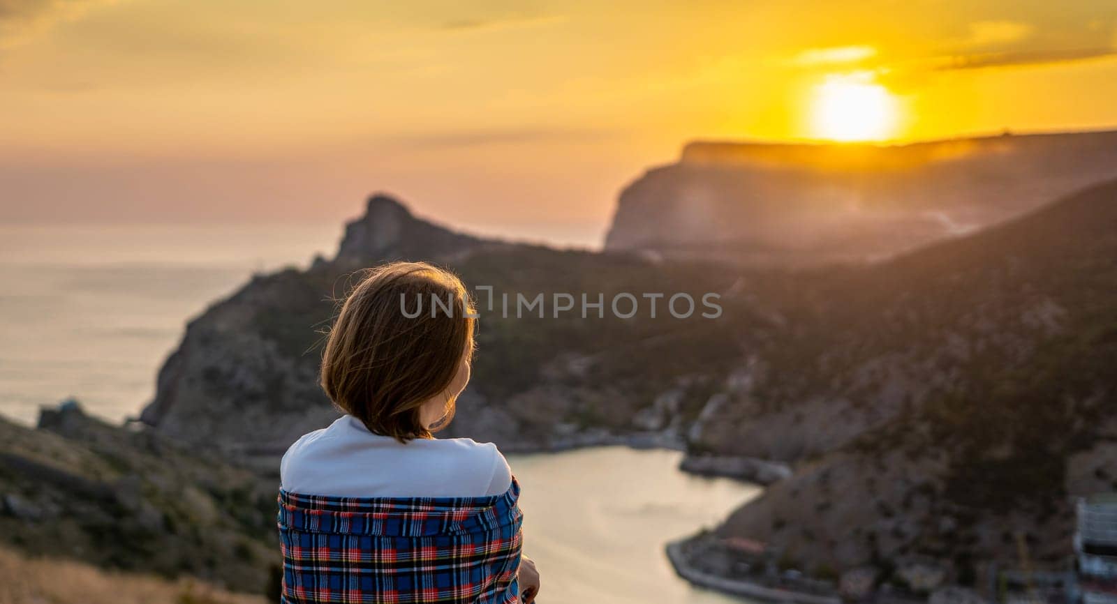 Happy woman on sunset in mountains. Woman siting with her back on the sunset in nature in summer. Silhouette