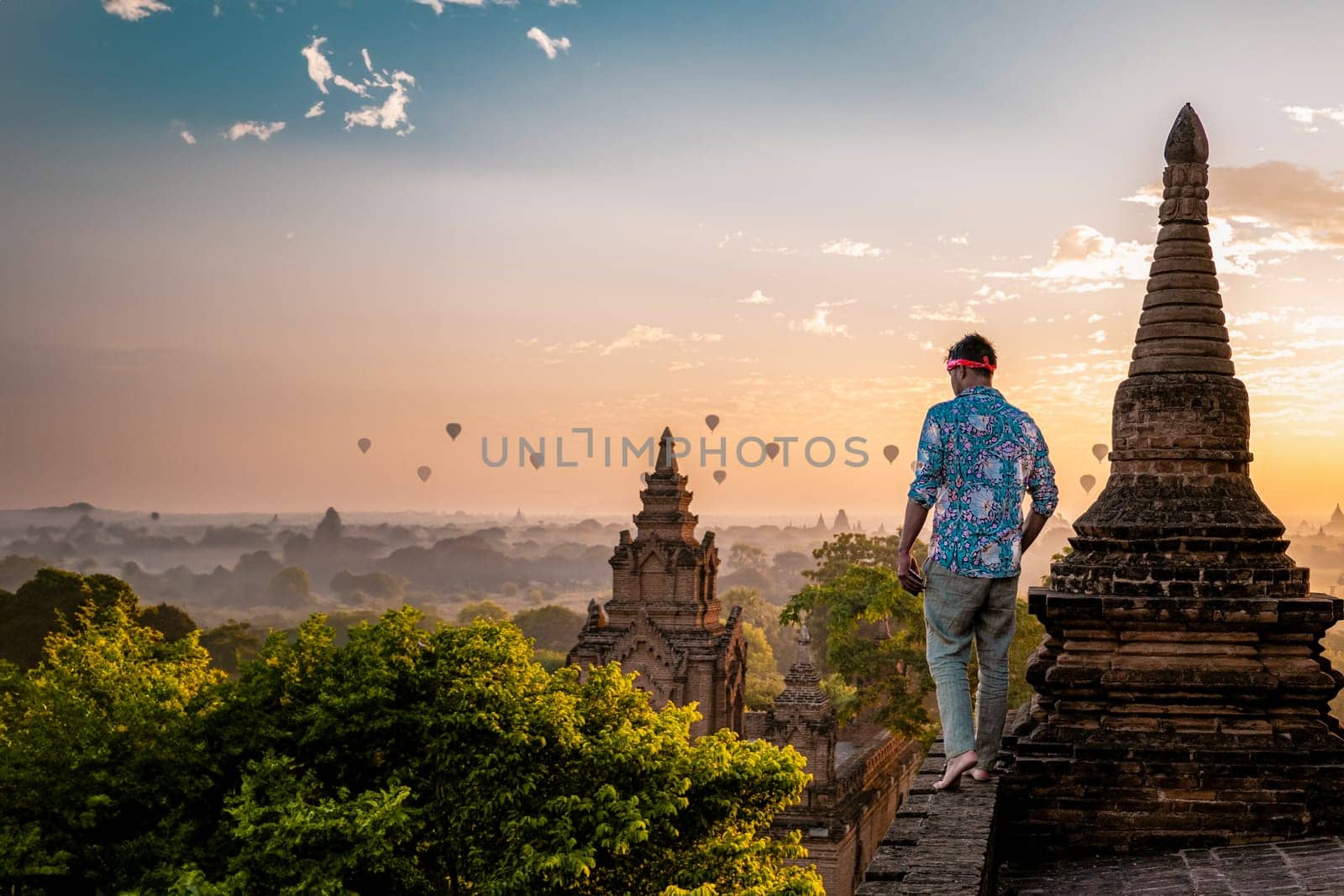 Bagan Myanmar, young men looking at the sunrise on top of an old pagoda temple by fokkebok