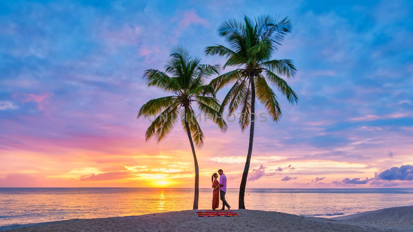 couple on the beach with palm trees watching the sunset at the tropical beach of Saint Lucia or St Lucia Caribbean Island. men and women on vacation in St Lucia a tropical island