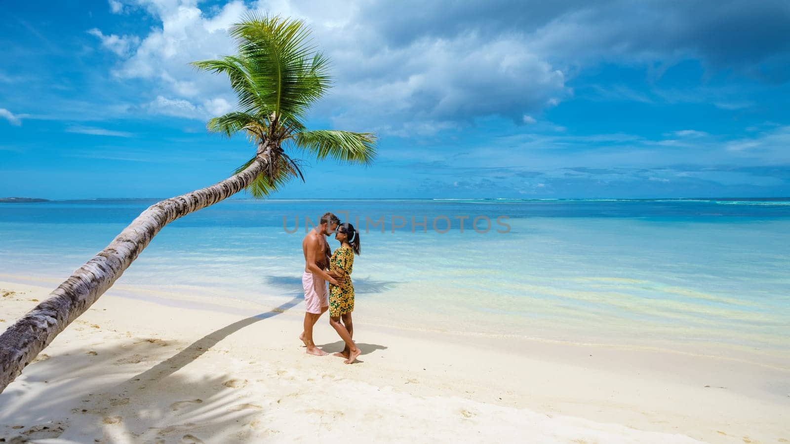 a couple of men and women on vacation at the beach of the Seychelles, men, and woman visit Anse Royale Beach in Mahe Island Seychelles