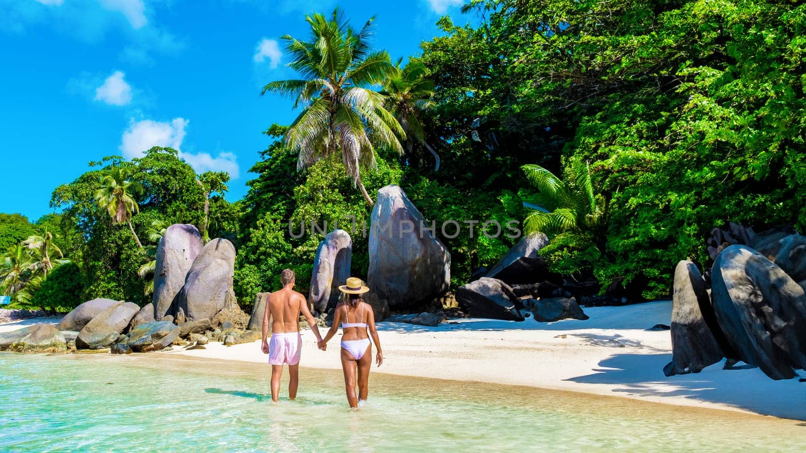 Praslin Seychelles tropical island with withe beaches and palm trees, a couple of men and women mid age on vacation at Seychelles visiting the tropical beach Anse Lazio Praslin Seychelles.