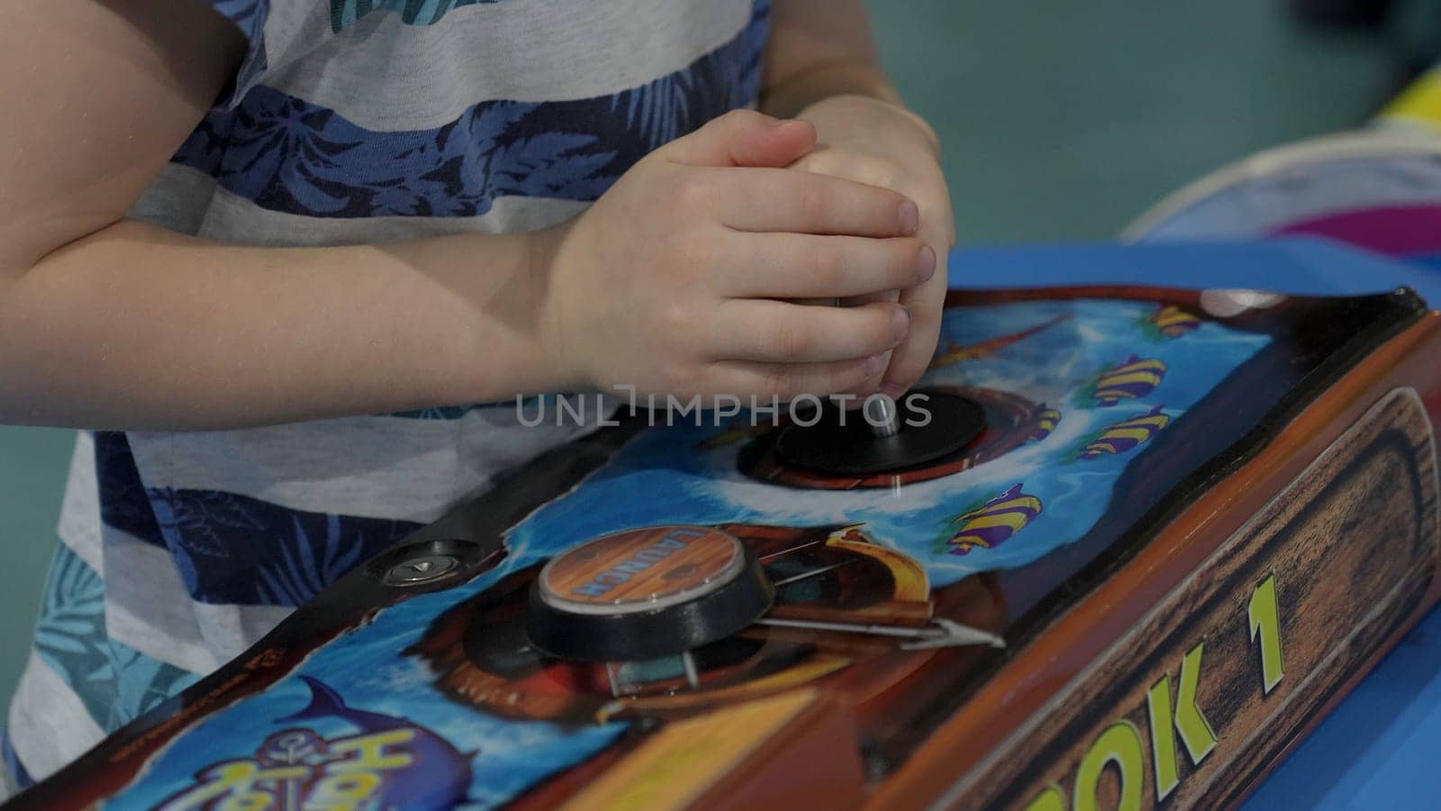 Denmark - Copenhagen, June 5, 2023: Close up of child at the control panel of a game machine. Clip. Boy or girl playing slot machine