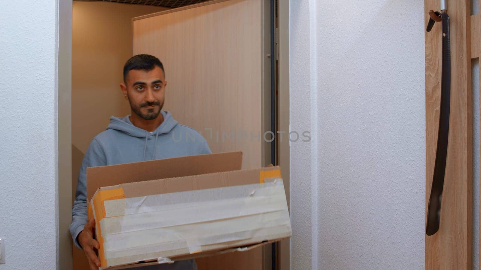 A man entering the apartment with a box. Media. An adult man entering a new apartment with large boxes. by Mediawhalestock