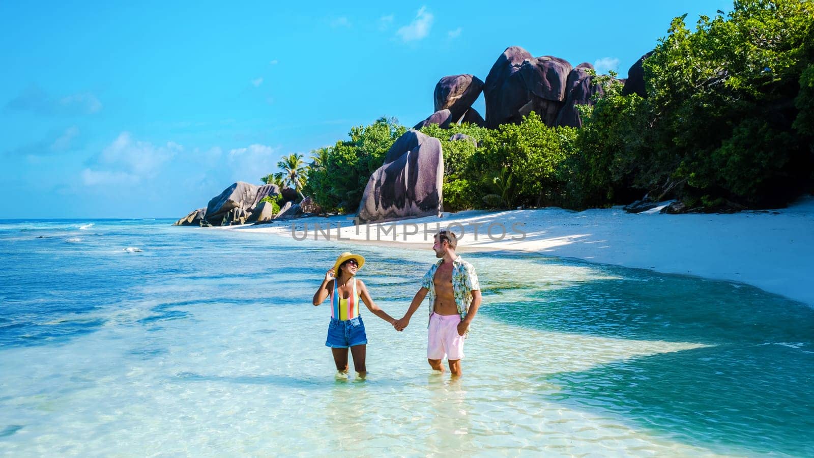 Anse Source d'Argent beach La Digue Island Seychelles, a couple of men and women walking at the beach at a luxury vacation. a couple swimming in the turqouse colored ocean of La Digue