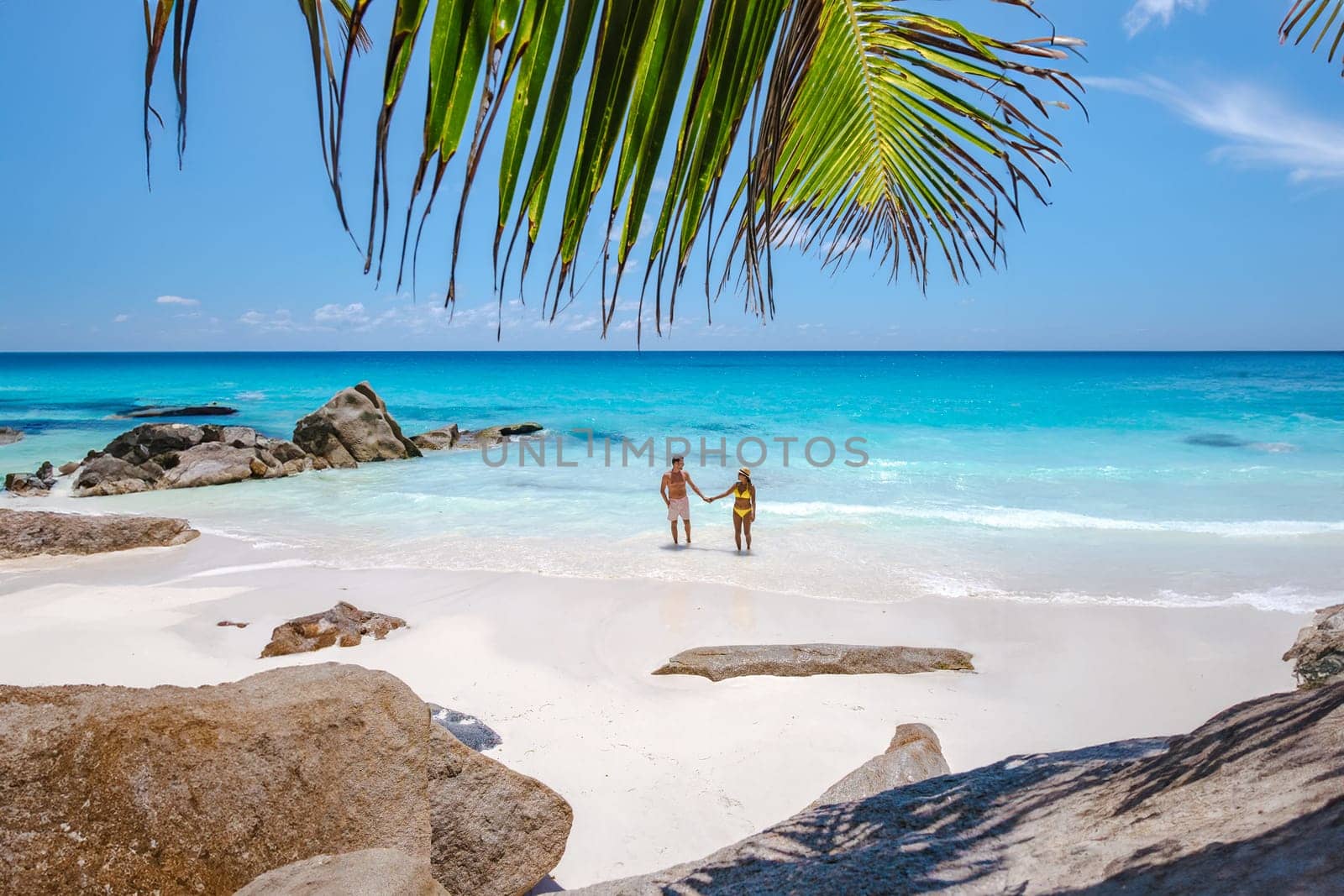 Anse Source d'Argent beach La Digue Island Seychelles, a couple of men and women walking at the beach at a luxury vacation. a couple swimming in the turqouse colored ocean