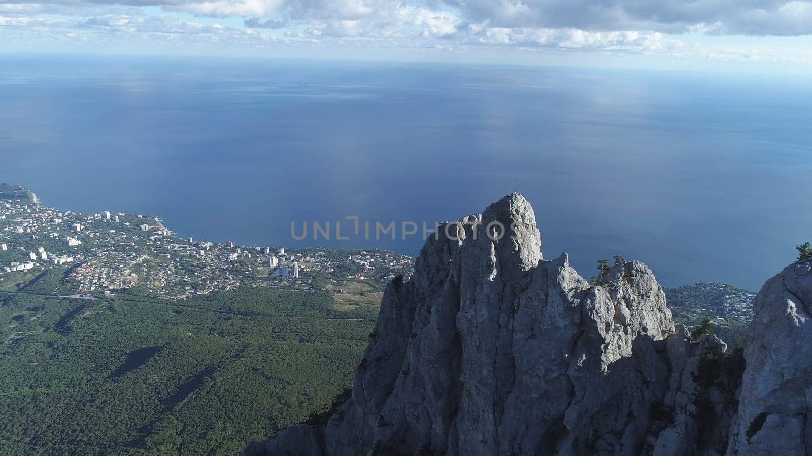Gorgeous scenery of the blue sea and small city on the shore against beautiful white cliff and standing people with flags in summer day. Amazing view from above