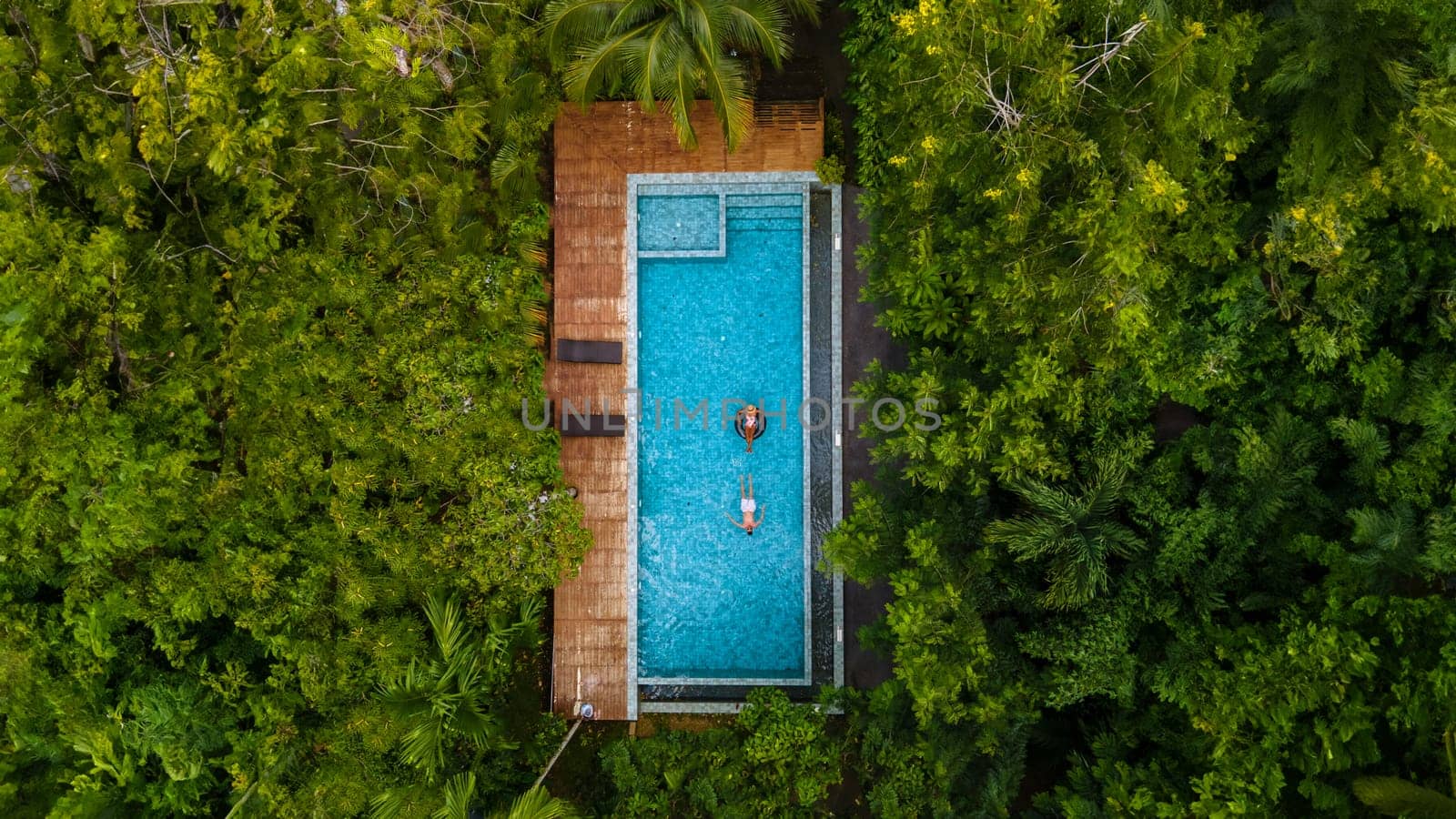 aerial drone view of swimming pool in the jungle of Krabi Thailand, aerial view with a drone above a swimming pool in the rainforest of Thailand. couple of men and women in pool during vacation