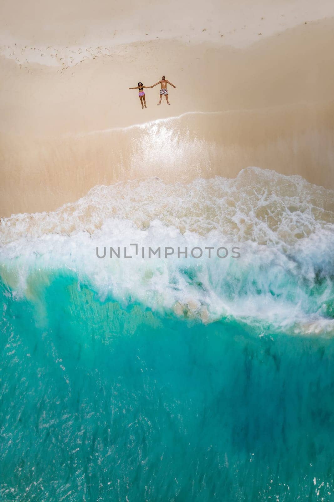 Man and woman lying down on a tropical beach, Drone view from above at a tropical beach in the Seychelles Cocos Island Seychelles, view from above at a tropical beach, couple on vacation