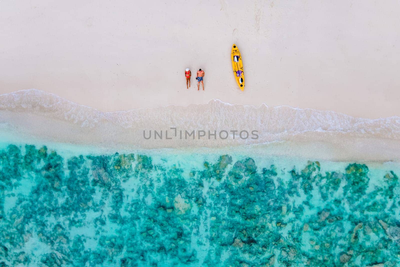 drone view at couple laying down on the beach of Koh Phi Phi Thailand during vacation with a kayak. couple on a beach with a kayak in Thailand at Koh Phi Phi Krabi