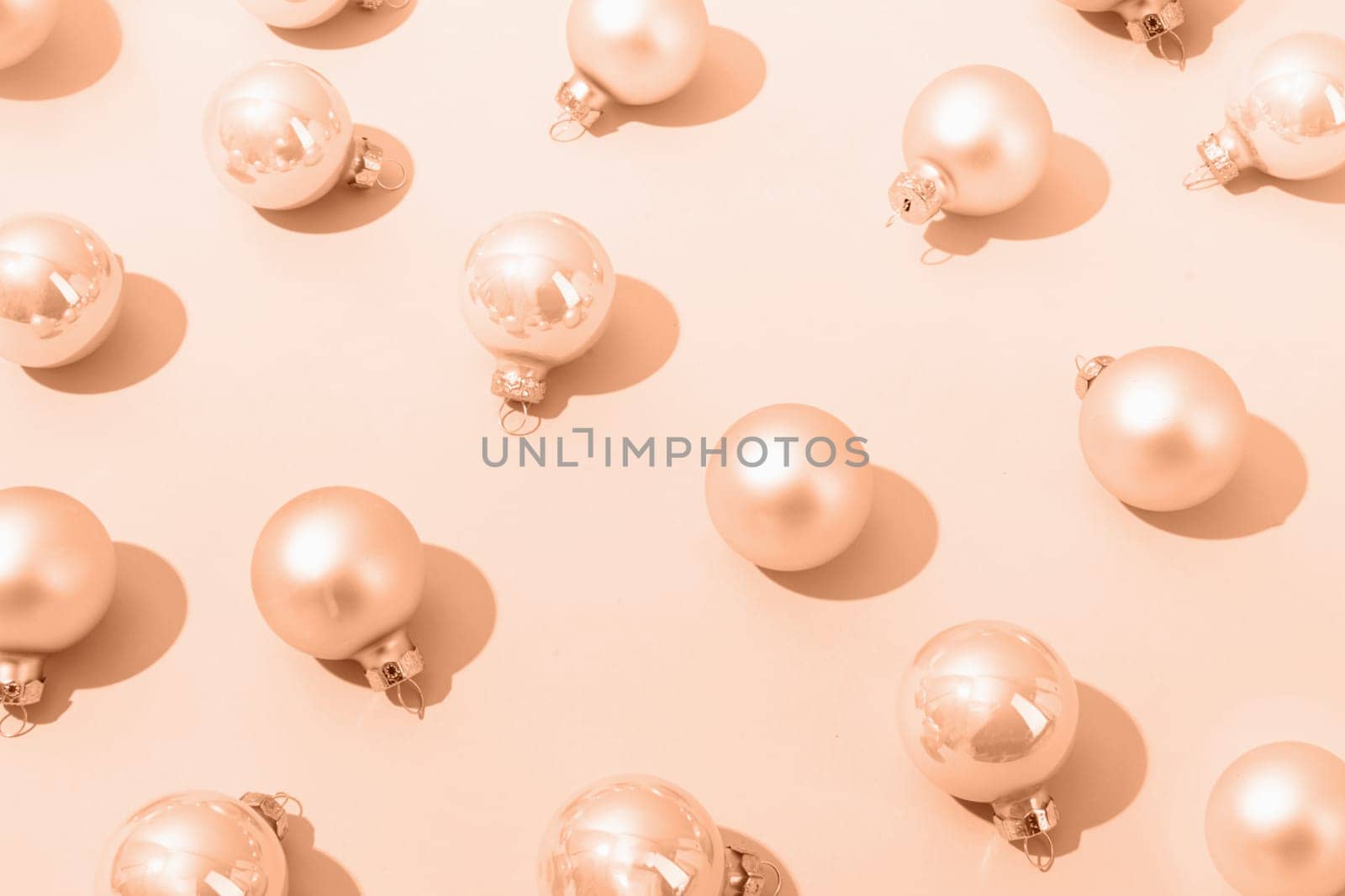 Color of the year 2024: Peach Fuzz. beige shiny christmas balls on beige pastel background, pattern. Winter, Cristmas and New year concept. Top view, flat lay