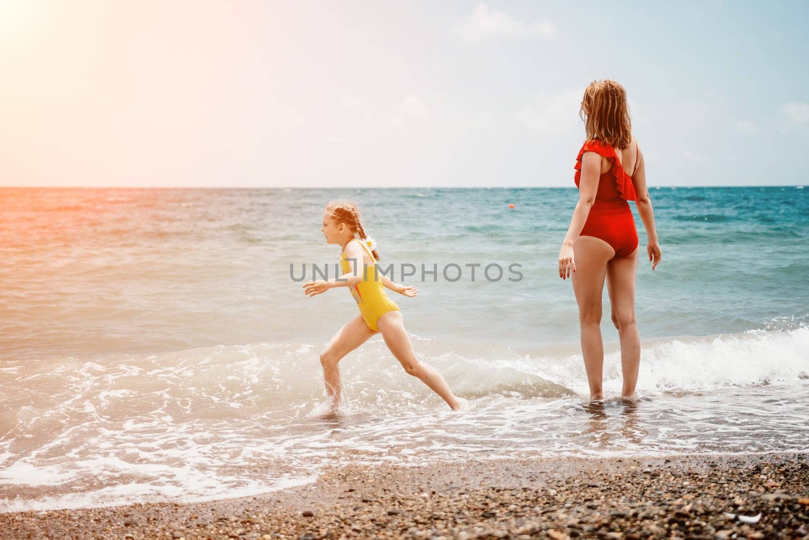 Happy loving family mother and daughter having fun together on the beach. Mum playing with her kid in holiday vacation next to the ocean - Family lifestyle and love concept.