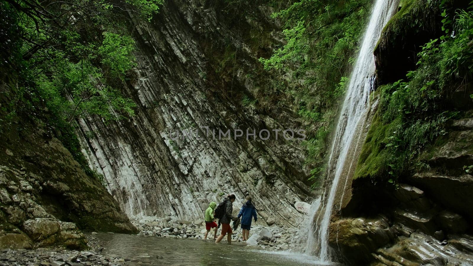 Jungle waterfall with walking in water. Creative. Concept of hiking, summer trip in wild nature