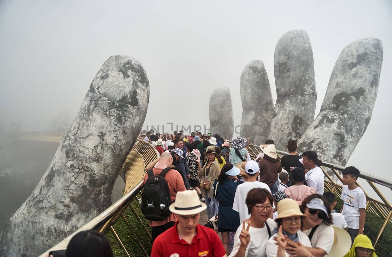 Danang, Vietnam - June 27, 2023: The Golden Bridge is lifted by two giant hands in the tourist resort on Ba Na Hill by driver-s
