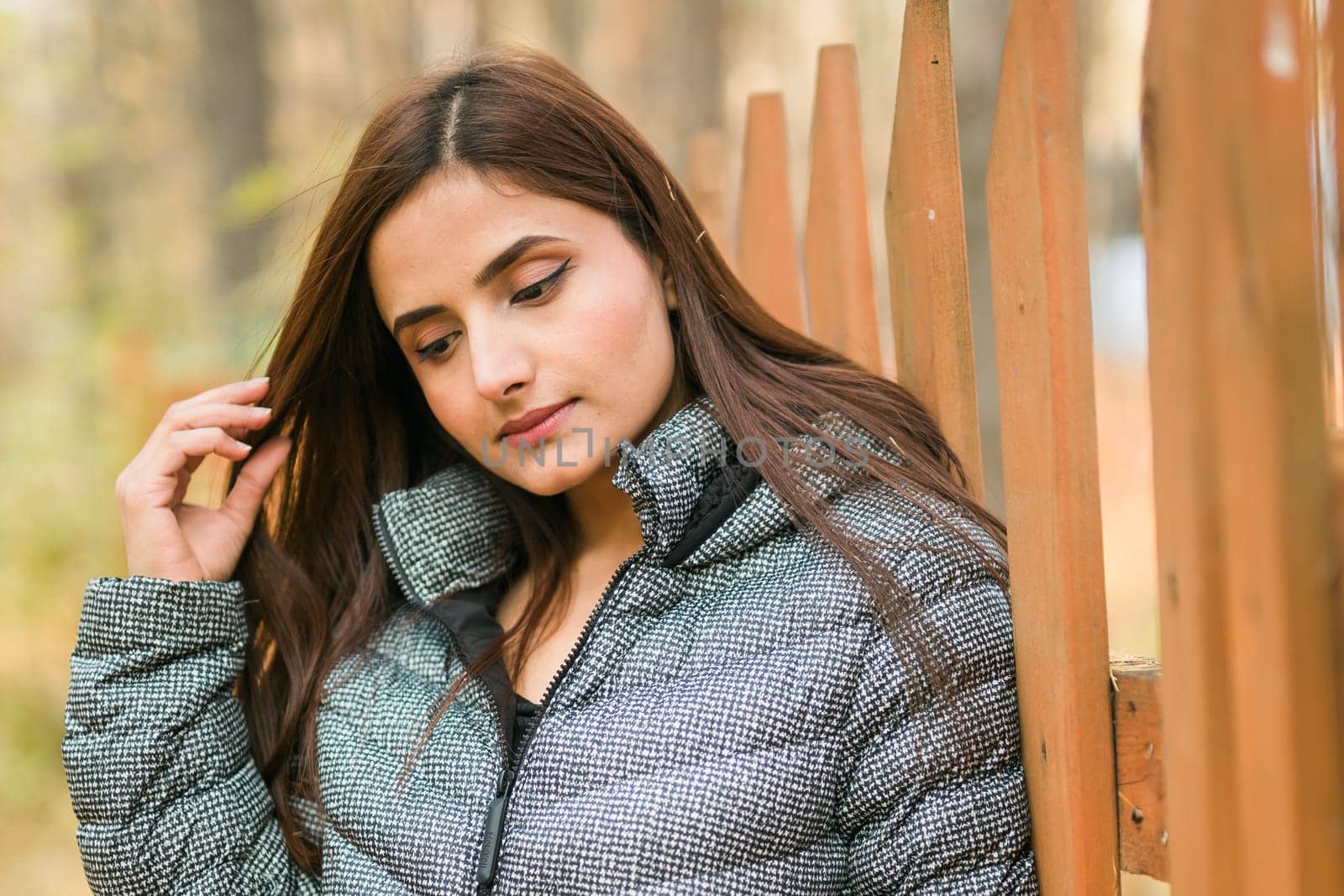 Close-up portrait of a young beautiful confident Indian Asian woman in fall outdoor. Happy and natural smiling female. Generation z and gen z youth