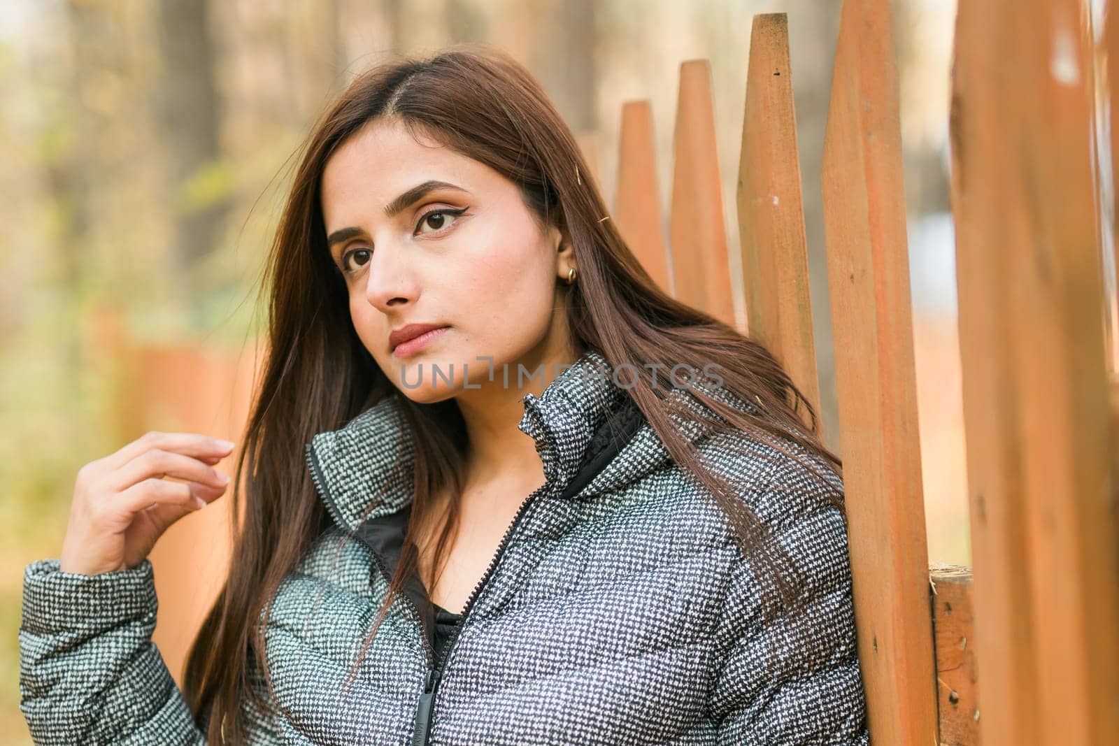 Close-up portrait of a young beautiful confident Indian Asian woman in fall outdoor. Happy and natural smiling female. Generation z and gen z youth