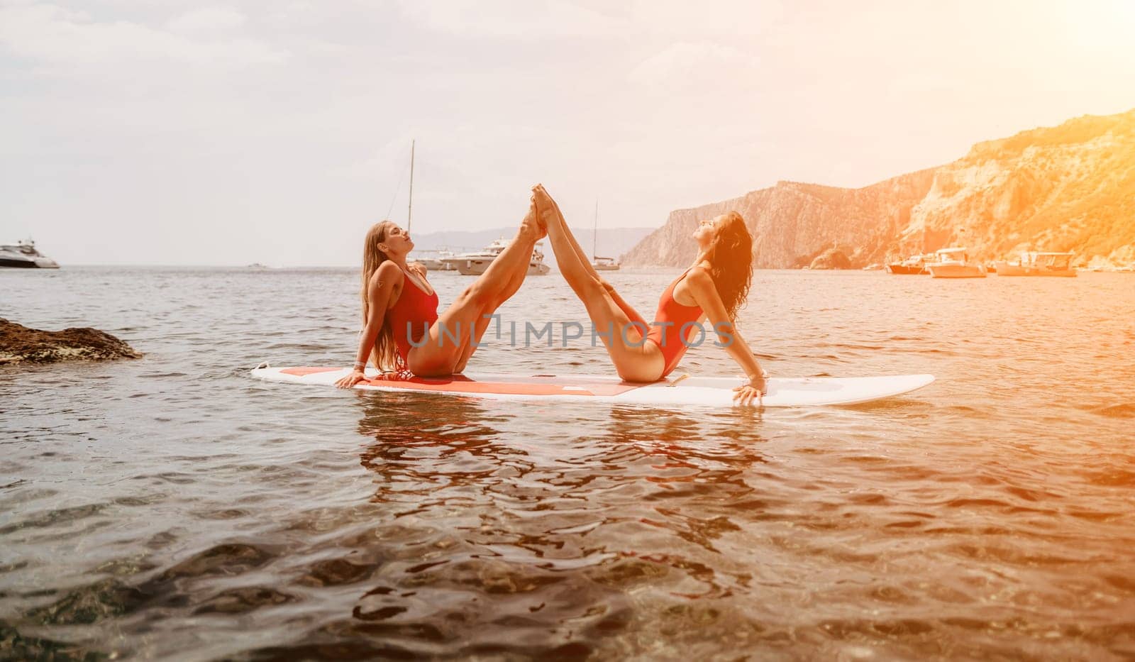 Woman sup yoga. Middle age sporty woman practising yoga pilates on paddle sup surfboard. Female stretching doing workout on sea water. Modern individual hipster outdoor summer sport activity