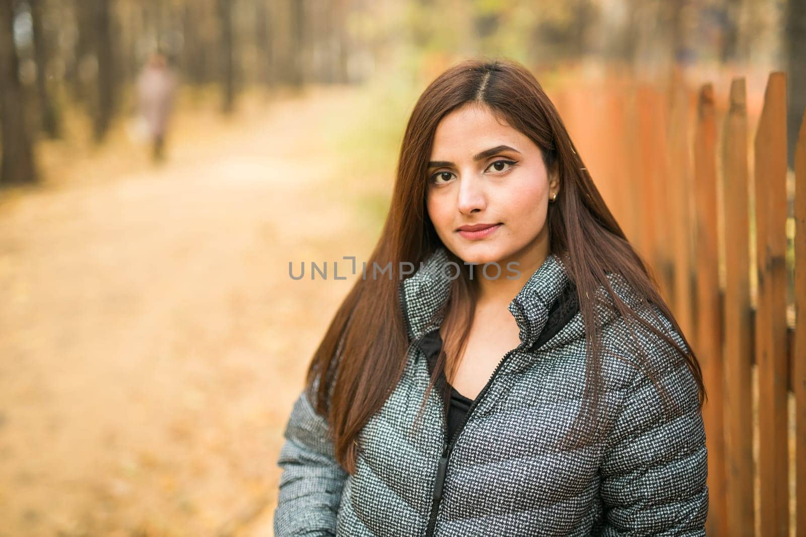 Beautiful indian woman generation z relaxing and feeling nature at autumn park in fall season. Diversity and gen z youth.