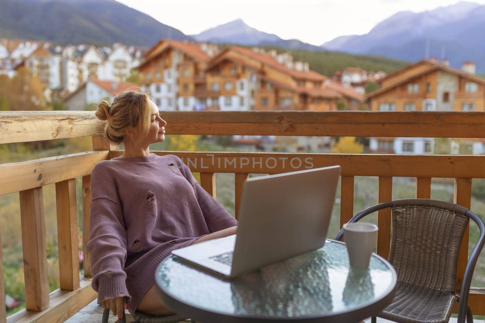 Girl working with a great view mountains. Workplace in country in backyard house in morning. Woman remote work on laptop while sitting at a table outdoors. Concept freelance lifestyle. Internet 5G