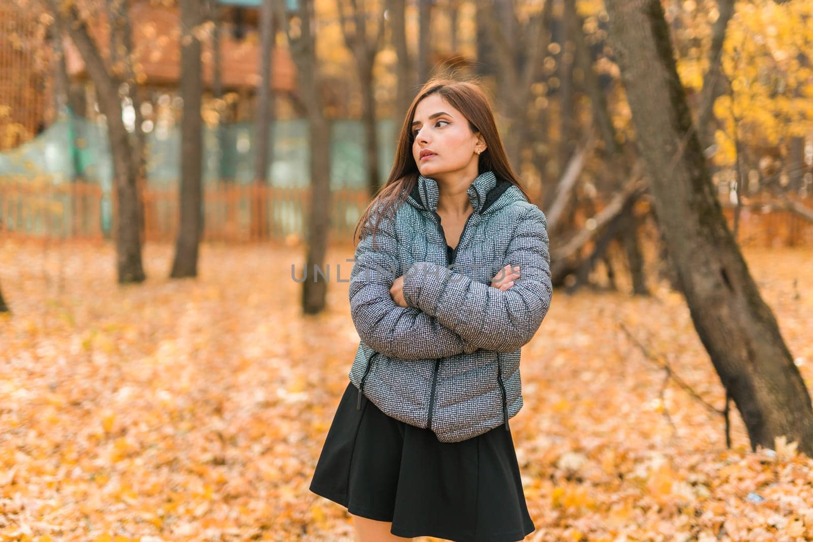 Beautiful indian woman generation z relaxing and feeling nature at autumn park in fall season copy space. Diversity and gen z youth by Satura86