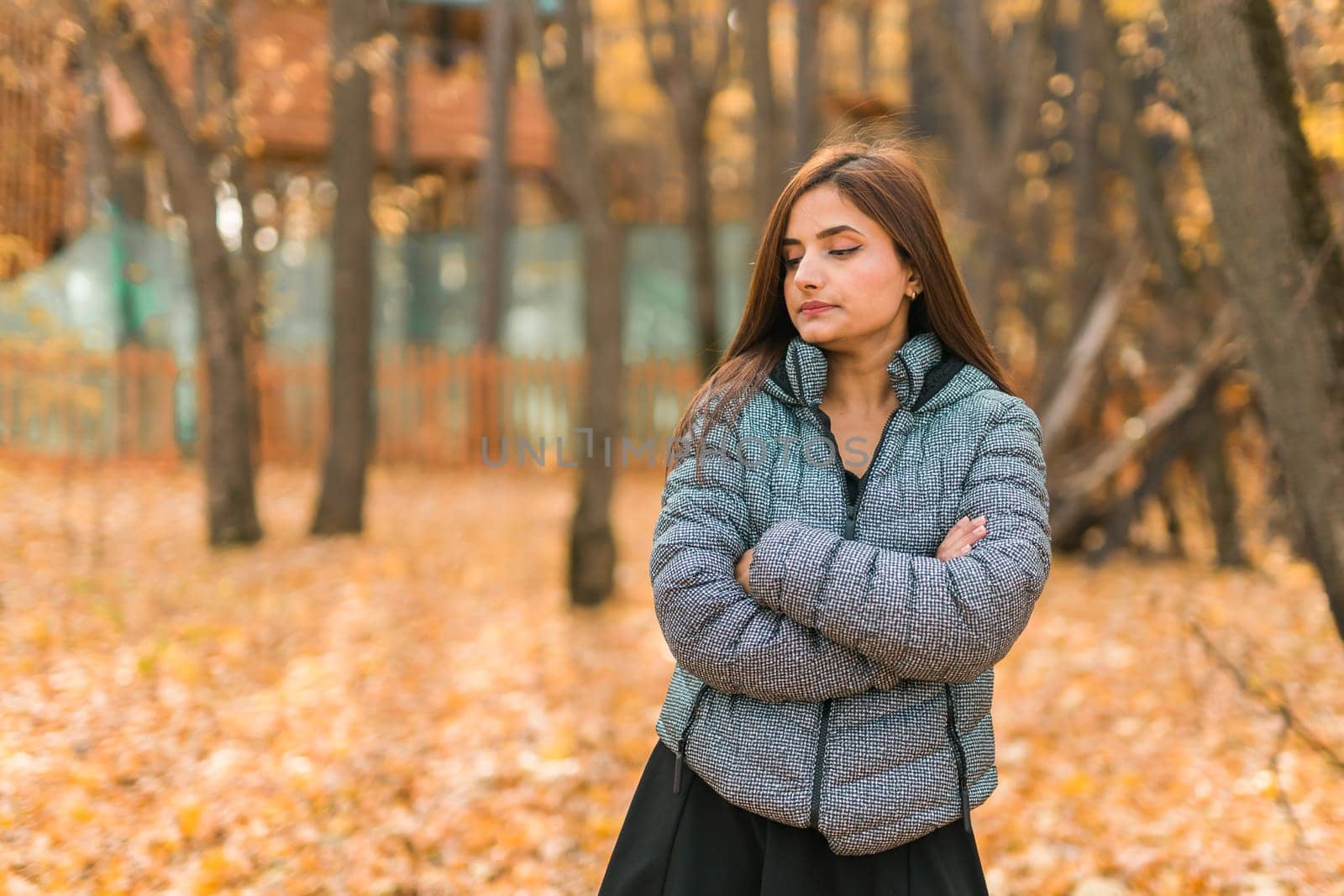 Beautiful indian woman generation z relaxing and feeling nature at autumn park in fall season copy space. Diversity and gen z youth by Satura86