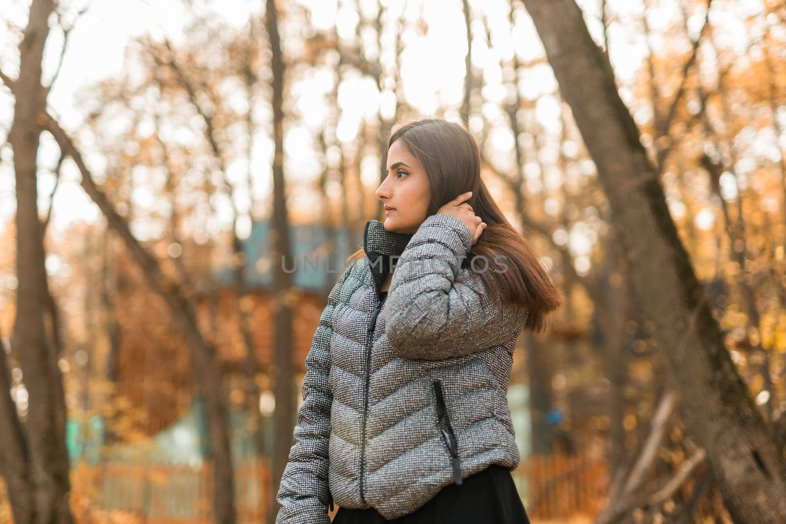 Close-up portrait of a young beautiful confident Indian Asian woman in fall outdoor. Happy and natural smiling female. Generation z and gen z youth