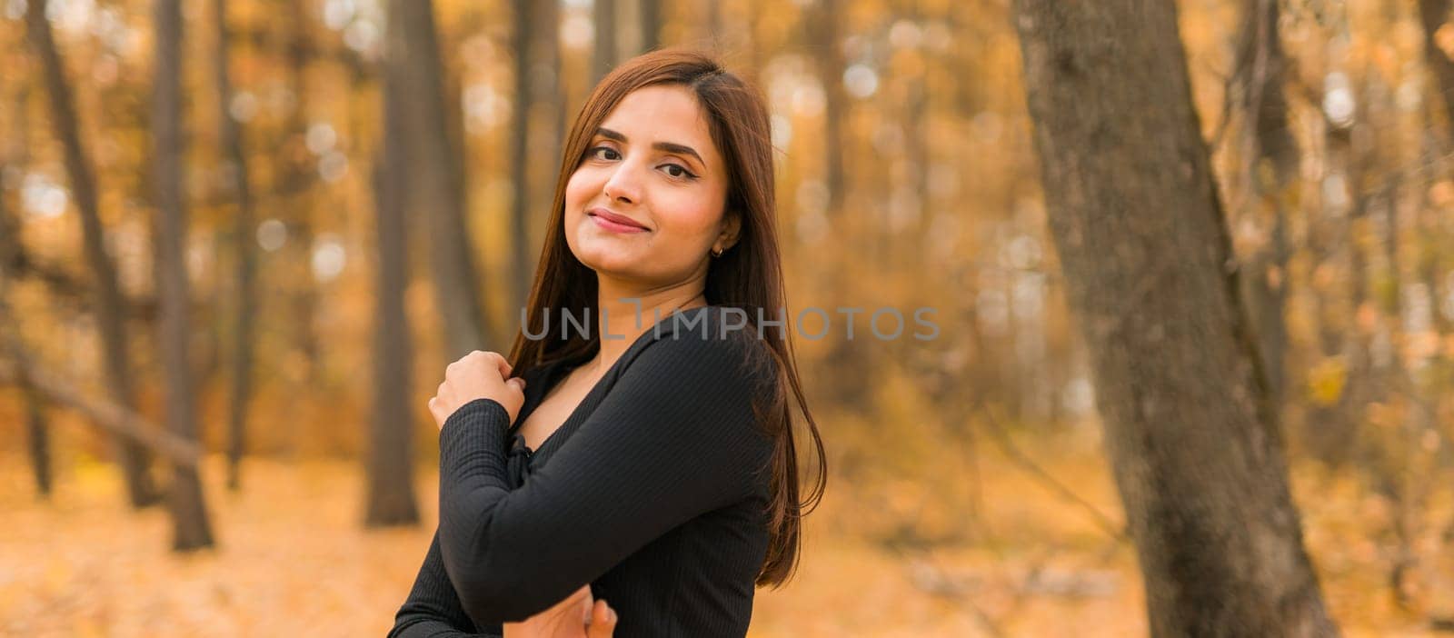 Close-up portrait of a young beautiful confident Indian Asian woman in fall outdoor. Happy and natural smiling female. Generation z and gen z youth