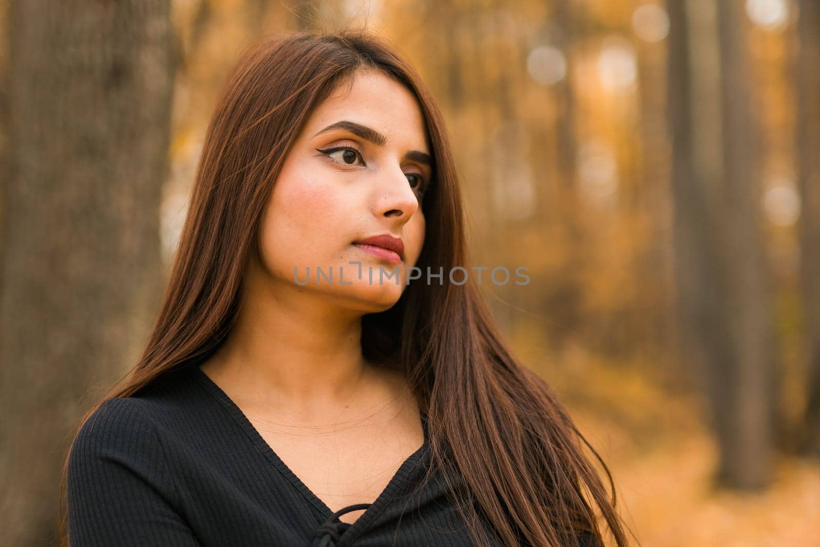 Close up portrait of pretty indian young woman enjoying warm autumn sunny day vacation outdoors copy space. Generation z and gen z concept. Fall Season by Satura86