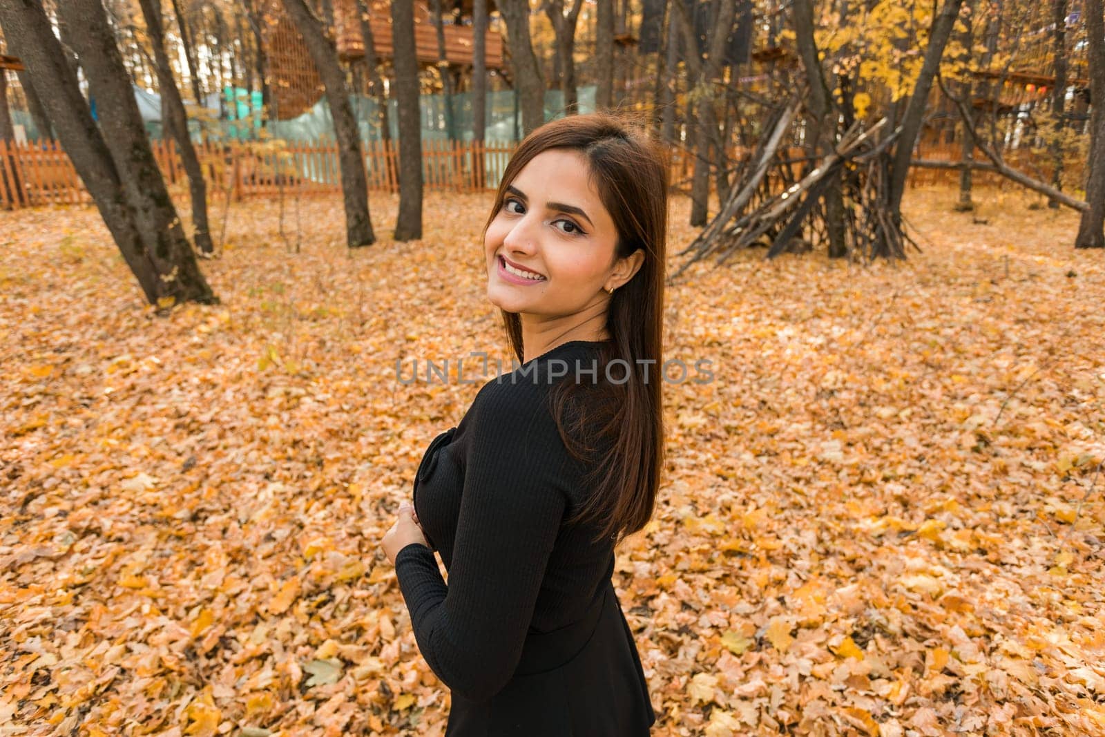 Close-up portrait of diversity young beautiful confident Indian Asian woman in black dress in fall outdoor copy space mockup. Happy and natural smiling female. Generation z and gen z youth concept by Satura86