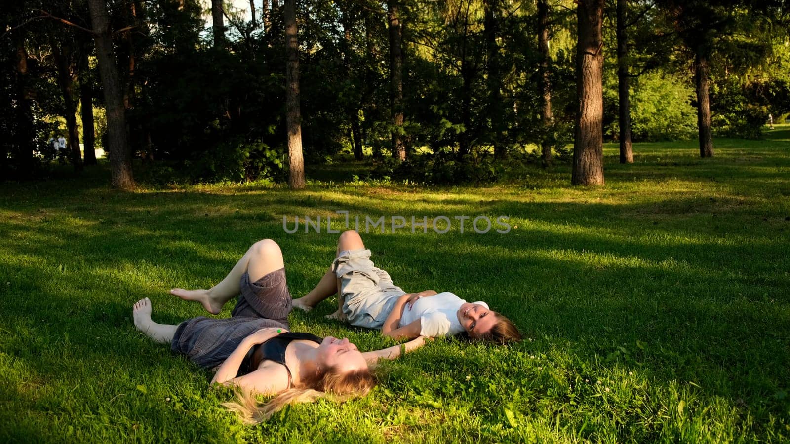 Rest in a quiet place. Concept. Two friends in summer clothes relaxing in a green clearing under the sun. High quality 4k footage