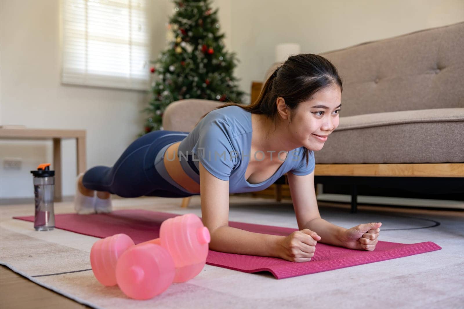 Happy Asian woman doing plank exercise or training for wellness with focus for healthy lifestyle at home.