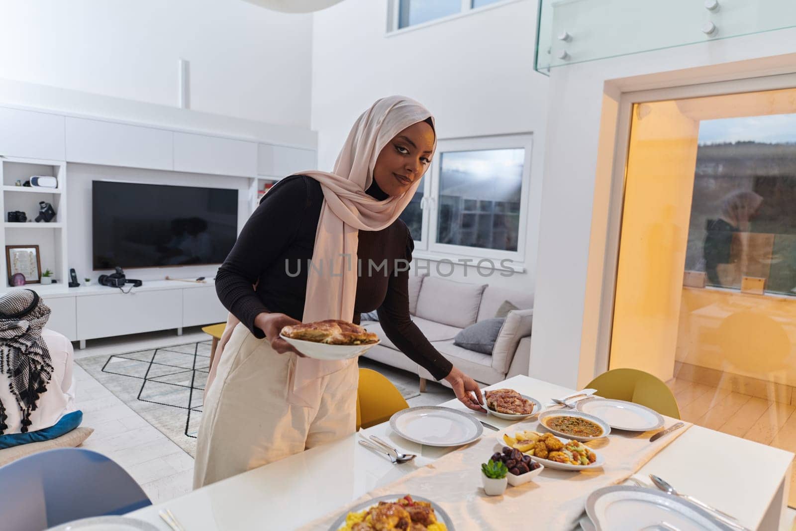 A young Arab woman gracefully prepares iftar for her family, delicately serving the table in the sacred month of Ramadan, capturing the essence of familial joy, cultural tradition, and spiritual devotion by dotshock