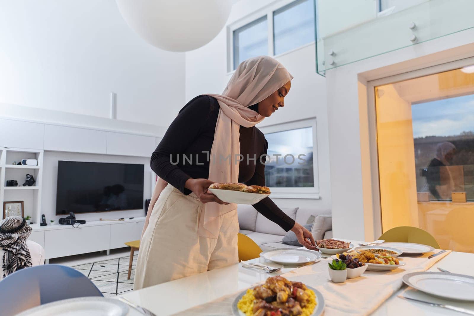 A young Arab woman gracefully prepares iftar for her family, delicately serving the table in the sacred month of Ramadan, capturing the essence of familial joy, cultural tradition, and spiritual devotion.