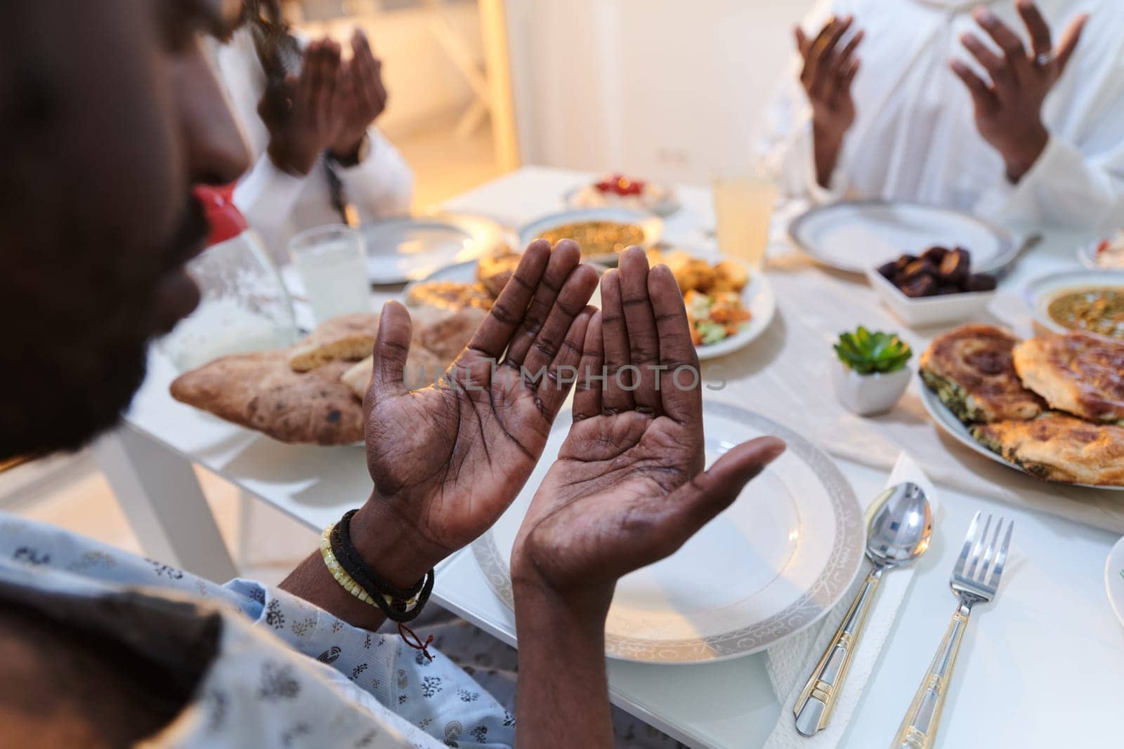 In the sacred month of Ramadan, a diverse Muslim family comes together in spiritual unity, fervently praying to God before breaking their fast, capturing a moment of collective devotion, cultural diversity, and familial joy in the midst of the holy celebration by dotshock