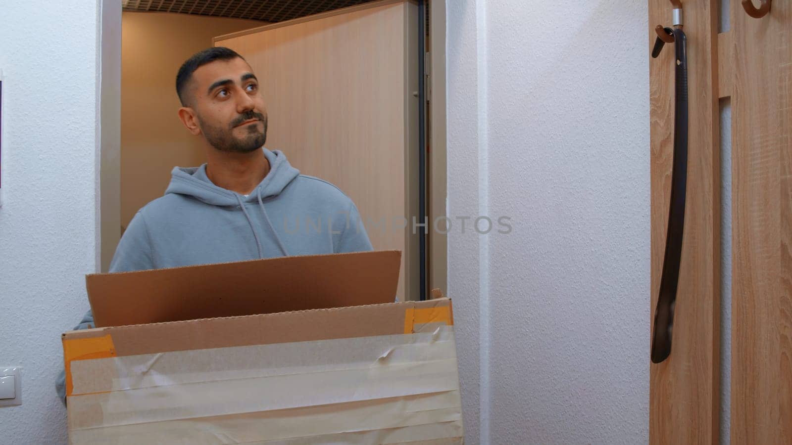 A man entering the apartment with a box. Media. An adult man entering a new apartment with large boxes. High quality 4k footage