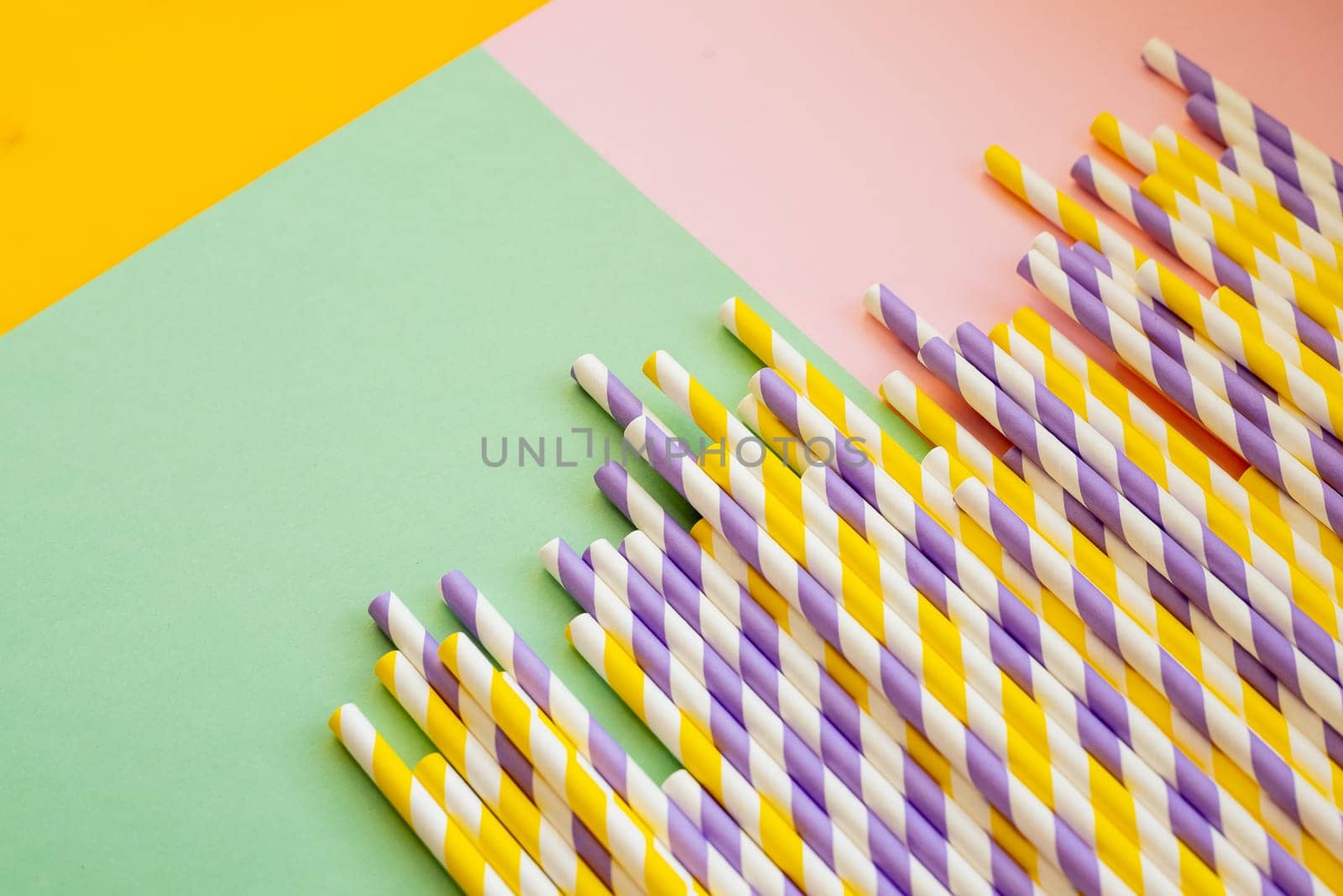 Drinking paper colorful straws for summer cocktails on light blue background with copy space. Top view.