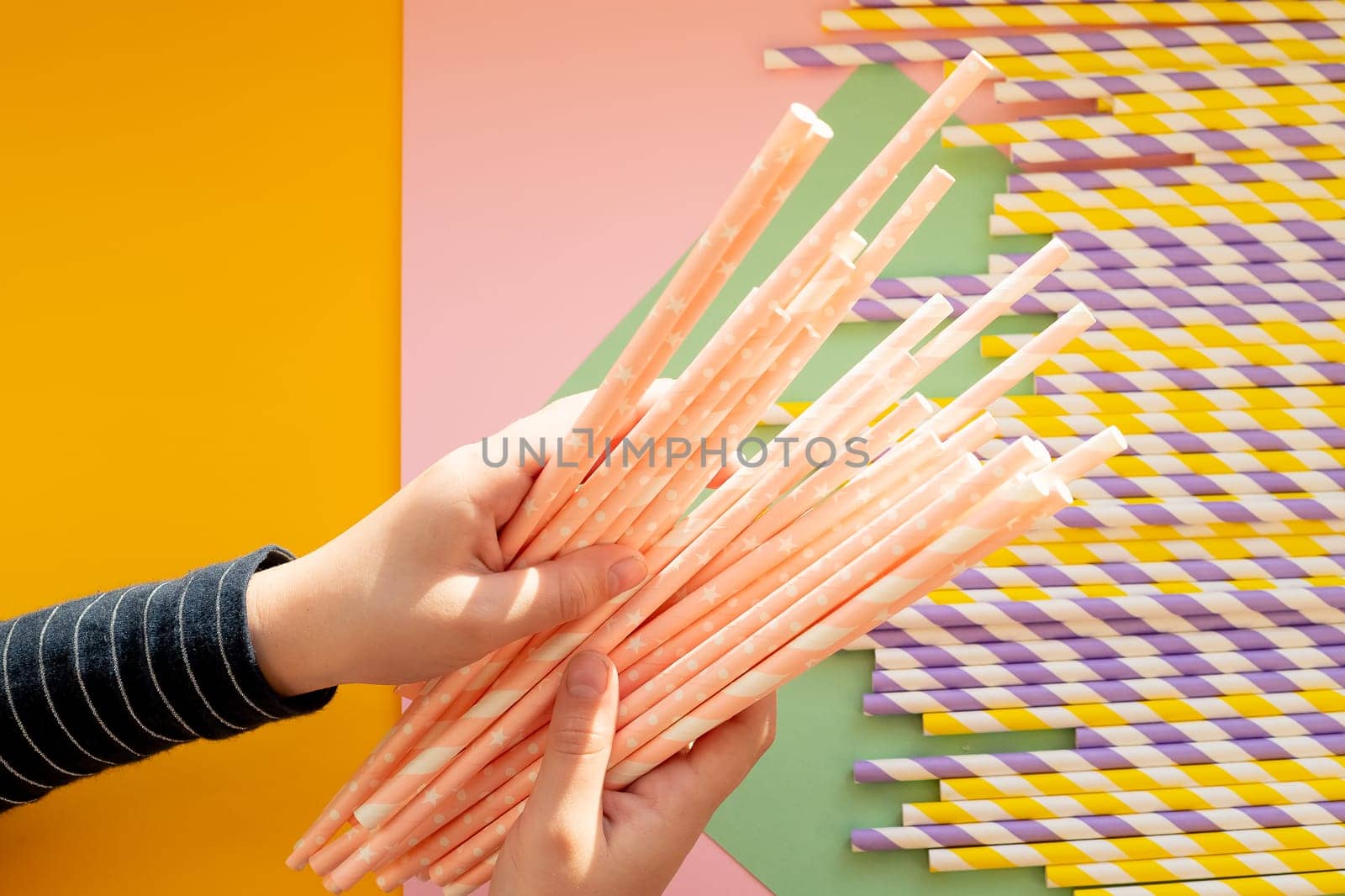 paper drinking straws with golden star polka dot pattern in stacked cups on green. Zero waste