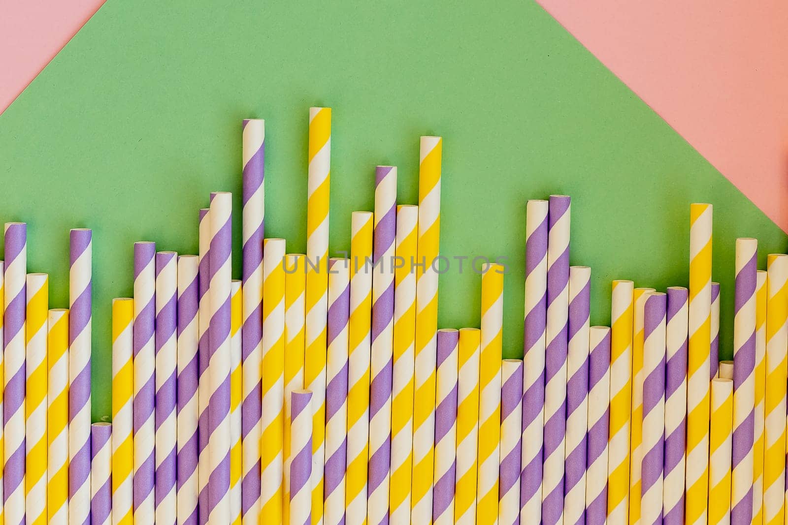 Drinking straws for party on white background. Top view of colorful paper disposable eco-friendly straws for cocktails.