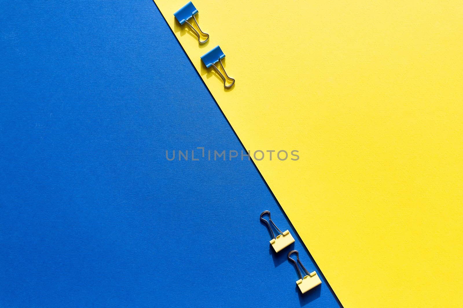 Set of colorful paper clips with copy space.business creativity concepts.Flat lay design.vivid color paper clips on yellow blue background. minimalism style, top view shot. by YuliaYaspe1979