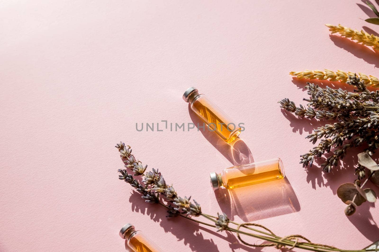 Bottle of essential oil with fresh herbal sage, rosemary, thyme and peppermint setup with flat lay on white wooden table.