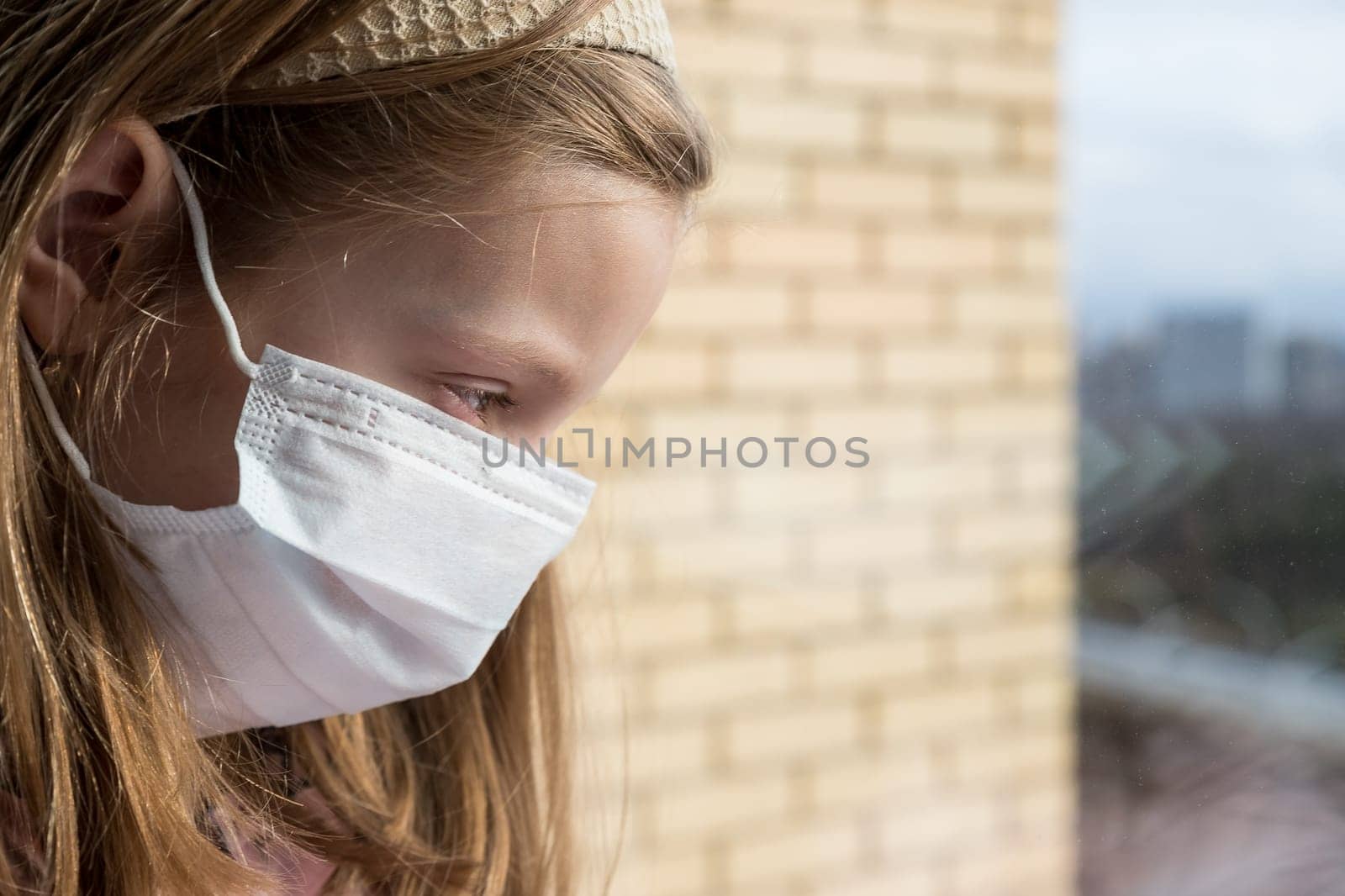 Coronovirus Quarantine Concept.A girl with a toy in a protective mask from the virus on her face