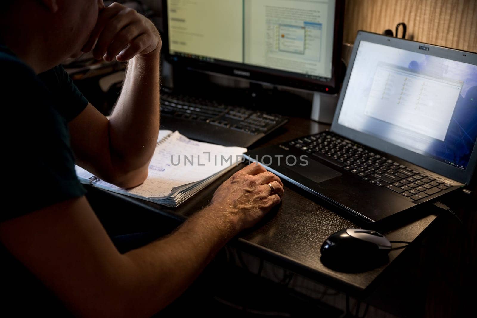 Casual man typing on mobile smart phone while working on laptop computer in coffee shop.