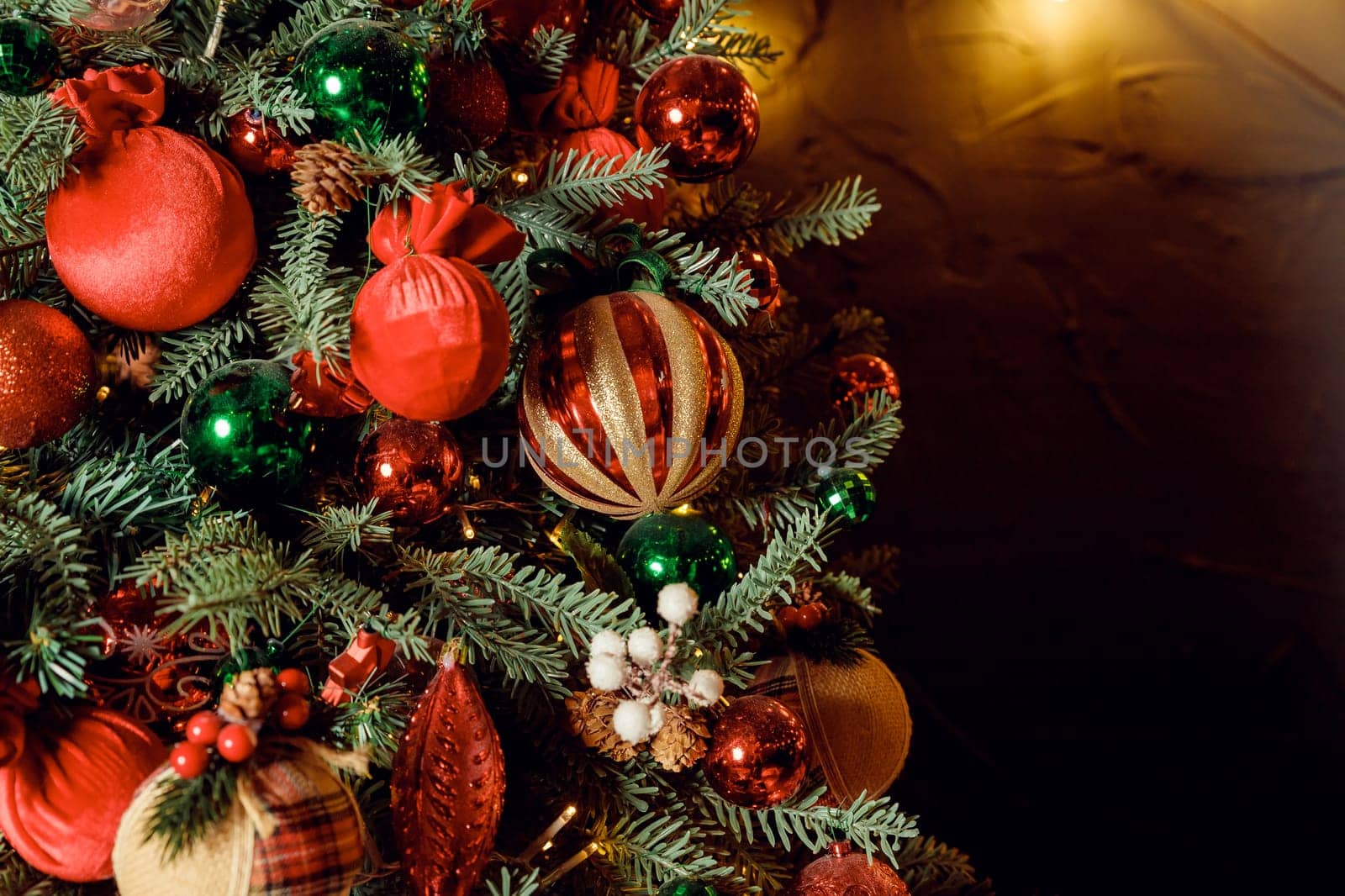 Christmas decorations on the holiday tree.Many colorful balls garland glowing lamps and red berries on the branches are sprinkled with snow.