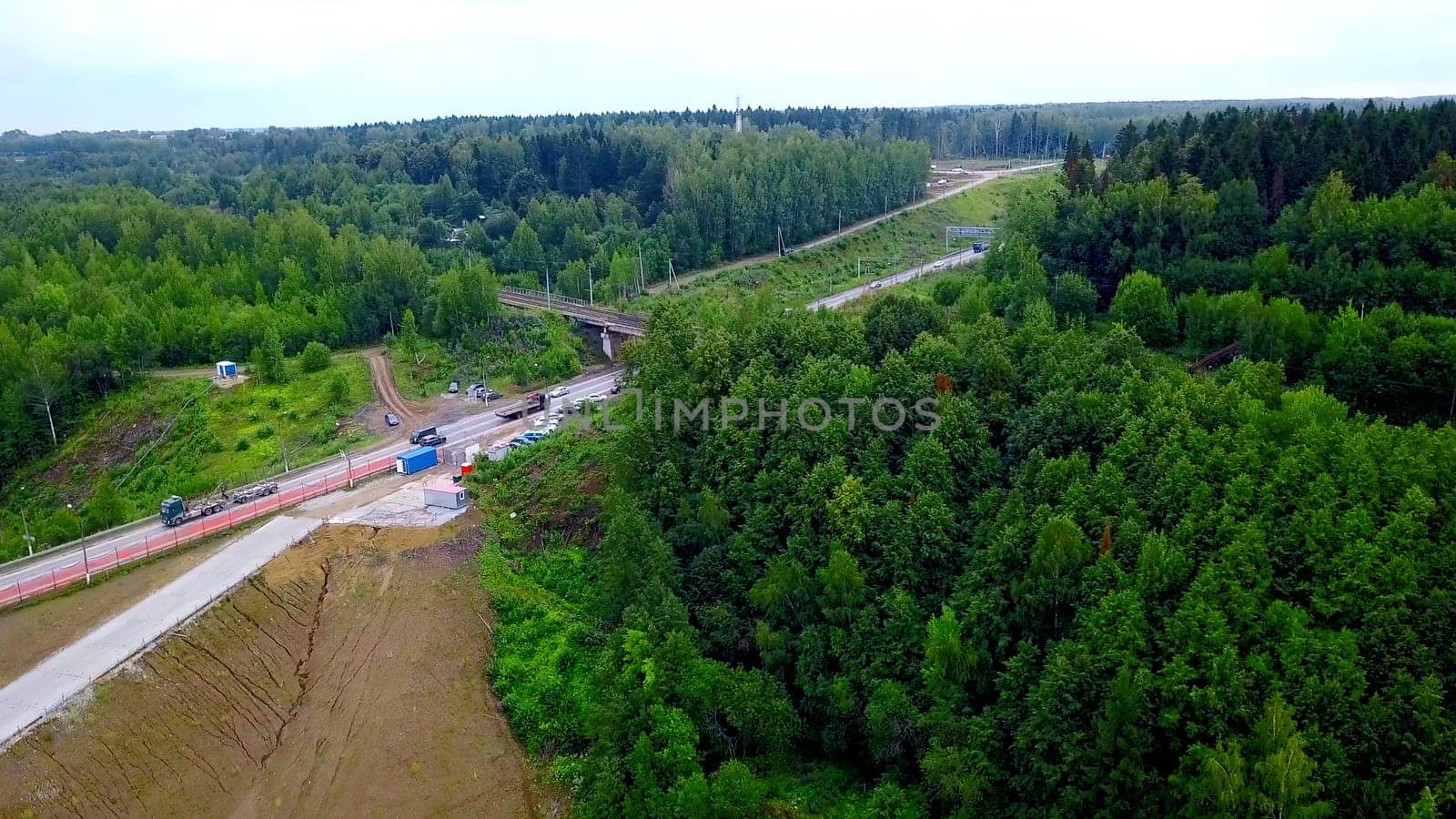 Aerial view of cars travelling in beautiful forested terrain. Clip. Vehicles driving on an asphalt road with a beautiful landscape. by Mediawhalestock