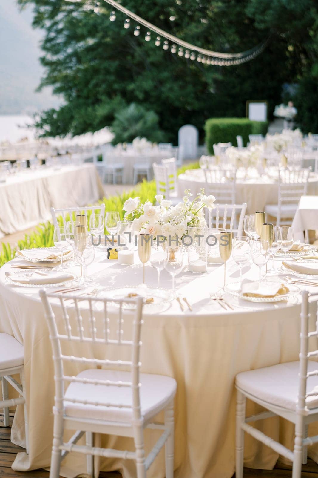 Set table with a bouquet of flowers, plates, glasses and bronze goblets stands in the garden. High quality photo