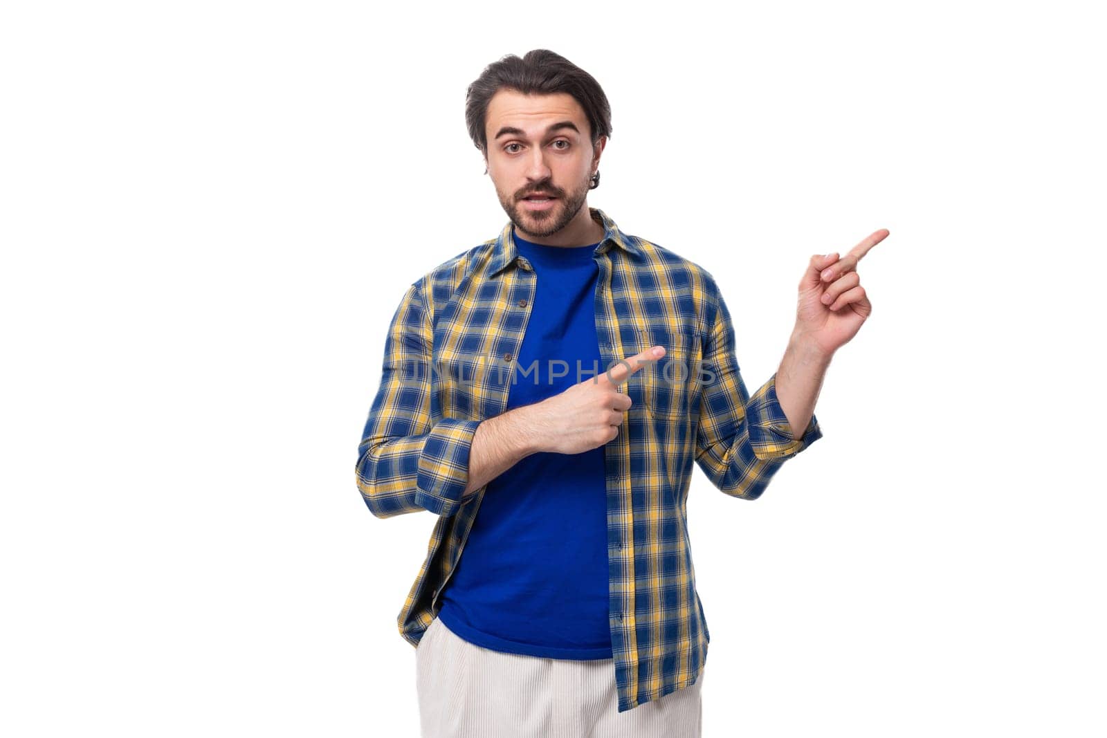 handsome brunette macho man with a beard in a blue shirt on a white background actively gesturing with his hands with copy space.